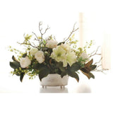 Elegant faux white amaryllis and magnolia leaf centerpiece in a brushed silver footed pot