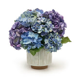 Bouquet of blue and purple hydrangeas in a textured vase on a white background