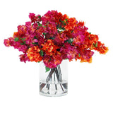 Colorful faux bougainvillea arrangement in a clear glass cylinder vase