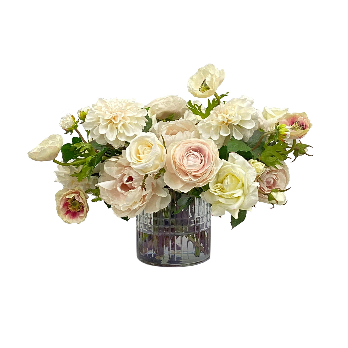 A natural looking cream colored faux rose and ranunculus tabletop arrangement in clear cut glass vase