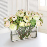 Luxury faux ranunculus and rose floral arrangement in a clear glass vase with soft cream blooms and greenery