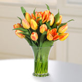 Realistic yellow and orange faux tulip arrangement displayed in an elegant flared glass vase