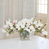 Elegant white faux magnolia centerpiece arranged in a rectangular clear glass vase