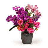 Bouquet of purple and pink flowers in a black vase on a white background