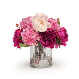 Bouquet of pink and purple flowers in a clear glass vase on a white background