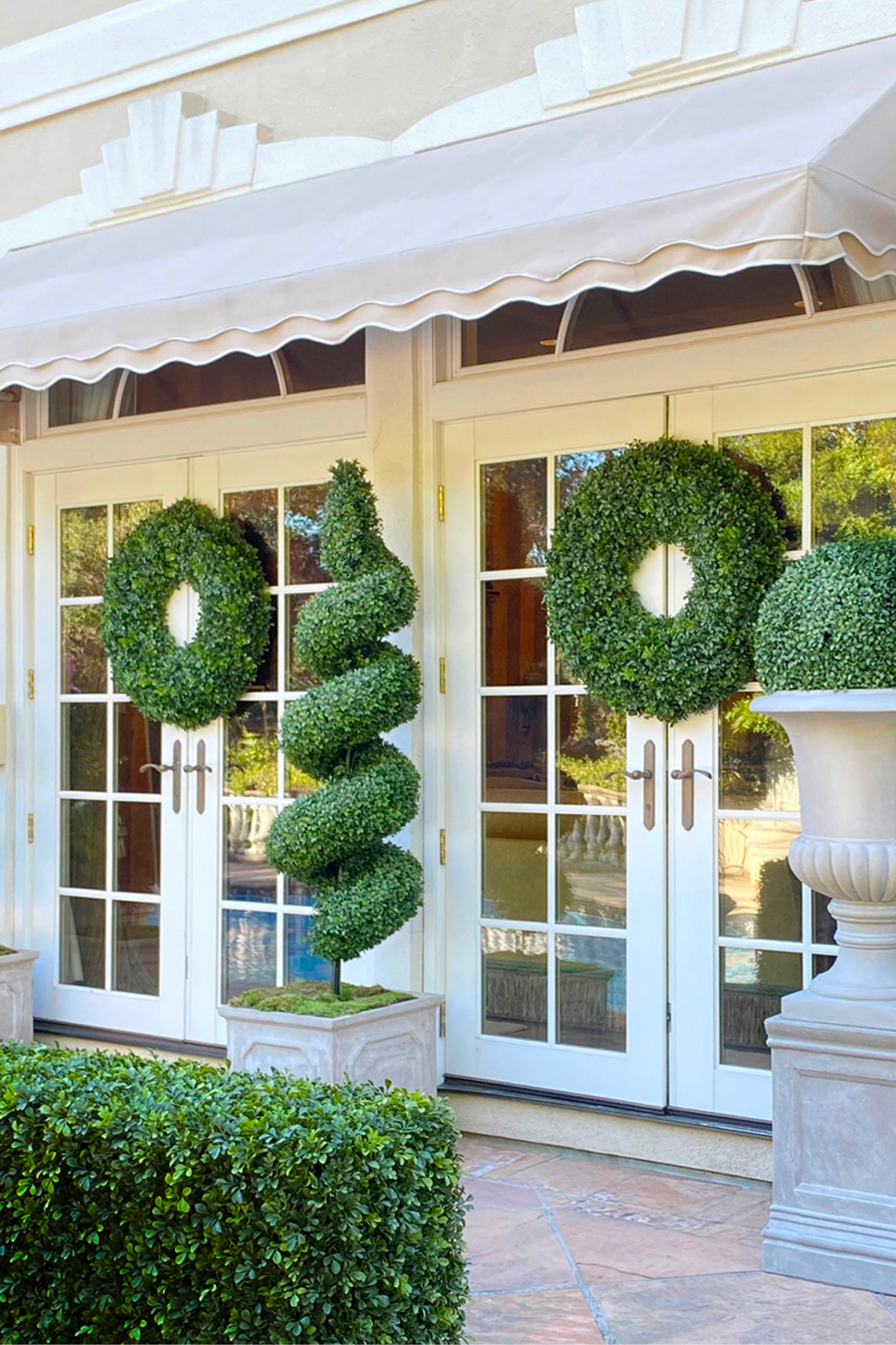 Greenery wreaths and topiaries outside a doorway