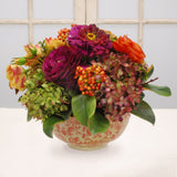 Mixed faux floral arrangement with magenta dahlias and hydrangeas displayed in a decorative longlife bowl