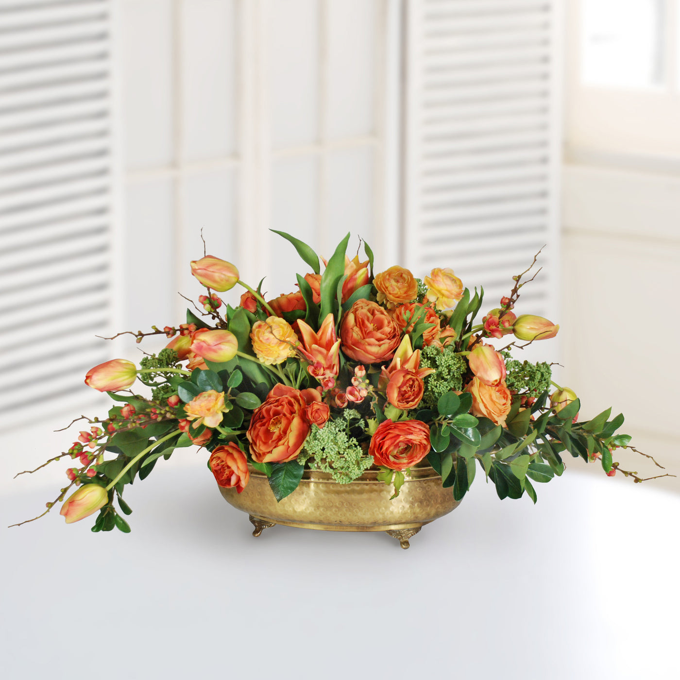 Mixed orange tulip and ranunculus in brass planter