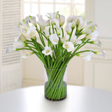 Tall white faux calla lily arrangement in a modern clear cylinder glass vase