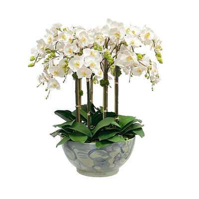 Tall white faux orchids in decorative ceramic bowl