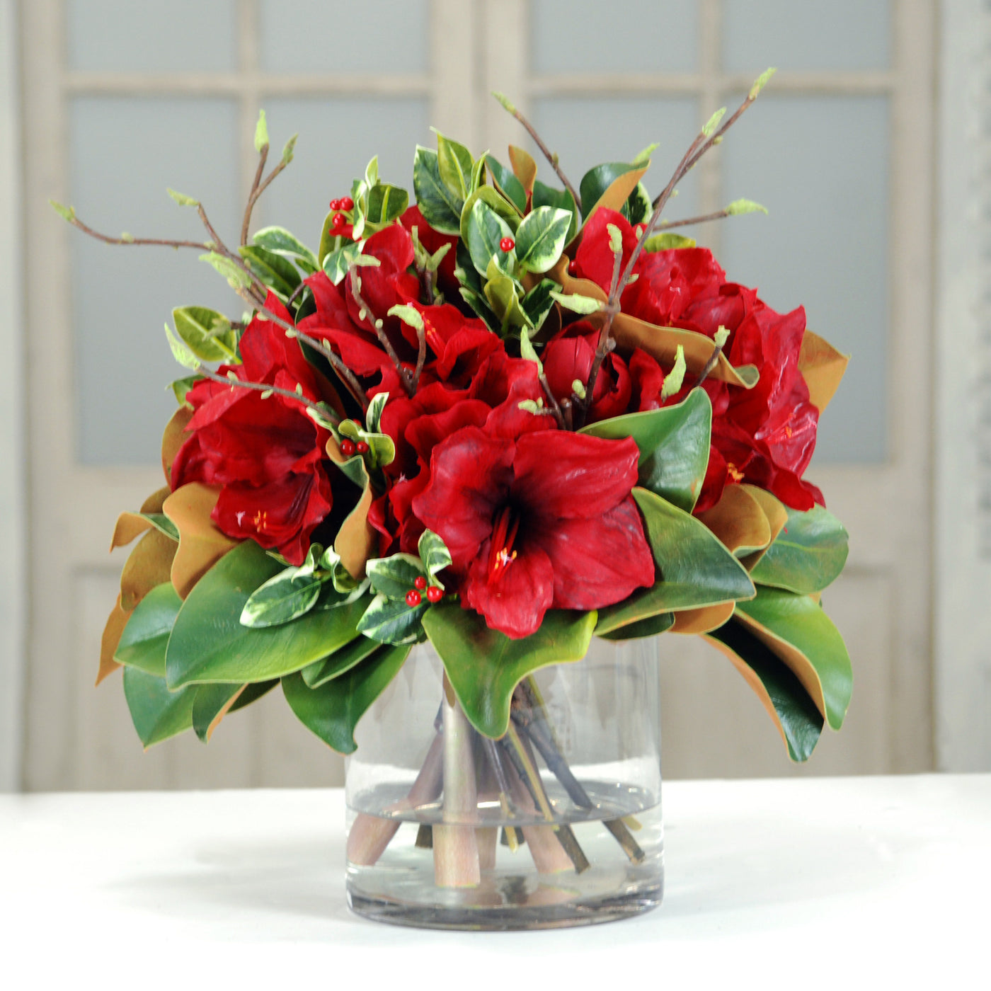 Red Amaryllis and Magnolia in Glass vase placed against background